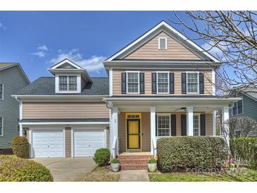 Charming two-story home with a welcoming front porch, neat landscaping, and a two-car garage at 142 Mills Ln, Fort Mill, SC 29708