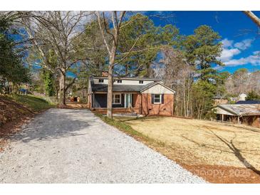 Charming brick home featuring a gravel driveway and beautiful landscaping on a sunny day at 428 Chester St, Lancaster, SC 29720