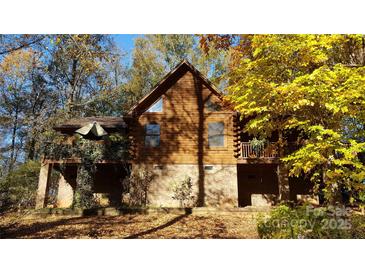 Charming log home featuring a brick foundation, triangular windows, and a deck with beautiful landscaping at 5912 Potter S Rd, Waxhaw, NC 28173
