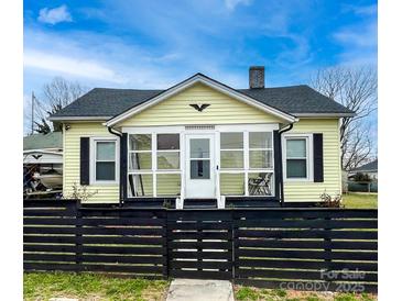 Charming yellow home featuring a cozy front porch and a stylish black fence at 101 Loya St, Mount Holly, NC 28120