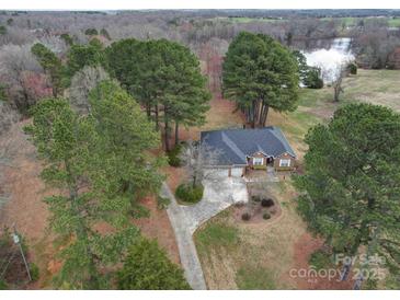 Expansive aerial view of a brick home nestled among mature trees, with a long drive and lake views at 805 Stack Rd, Monroe, NC 28112