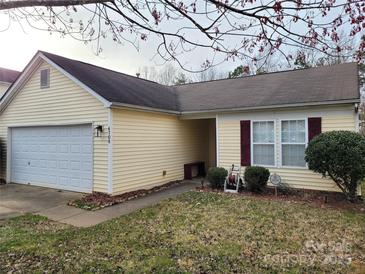 Charming yellow home with a one-car garage and manicured front lawn at 6708 Burning Oak Ln, Charlotte, NC 28216