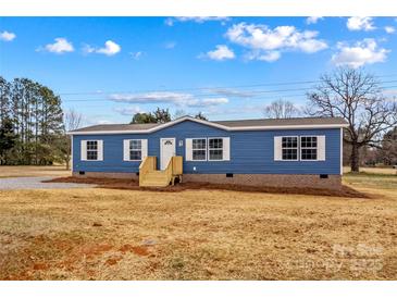 Inviting blue manufactured home with white trim and new porch steps in a rural setting at 114 Hallmark Estates Dr, Statesville, NC 28625