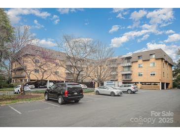 Exterior view of a brick condo building with mature landscaping and parking at 1323 Queens Rd # 202, Charlotte, NC 28207