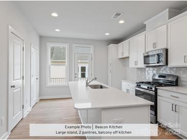 Bright, modern kitchen with white cabinets, stainless steel appliances, and a large island with quartz countertops at 214 Gilead Rd, Huntersville, NC 28078