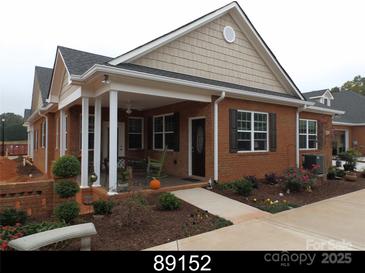 Charming brick home featuring a welcoming front porch, black shutters, and beautifully landscaped yard at 2227 Cashmere Ct, Denver, NC 28037