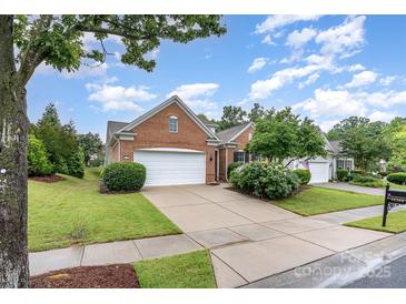 Charming brick home featuring an attached two-car garage, well-manicured lawn, and lush landscaping at 14309 Stonewater Ct, Fort Mill, SC 29707