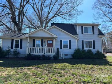 Charming two-story home featuring light siding, a cozy front porch, and classic black shutters at 1611 Old Hickory Grove Rd, Mount Holly, NC 28120