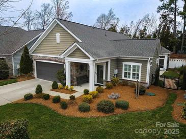 Charming single-story home showcasing a stone-accented porch, manicured landscaping, and attached garage at 16116 Lakeside Loop Ln, Cornelius, NC 28031