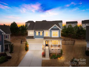 Charming two-story home with a welcoming front porch and landscaped yard, bathed in the warm hues of a sunset at 1660 Sassafras Ct, Fort Mill, SC 29715