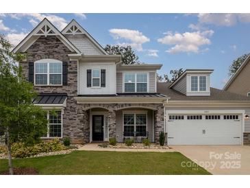 Charming two-story home with a stone facade, covered porch, manicured lawn, and two car garage at 17015 River Race Dr, Huntersville, NC 28078