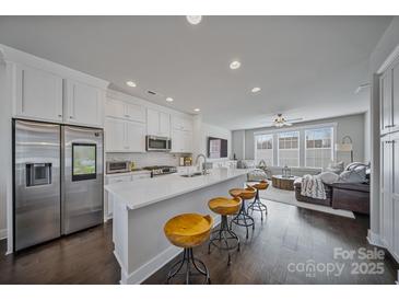 Modern kitchen features stainless steel appliances, white cabinetry, and a large center island with seating and an open view to the living room at 546 Amalfi Dr, Davidson, NC 28036