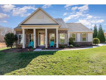 Charming single-story home with a manicured lawn, stone accents, and a welcoming front porch with blue chairs at 7034 Pin Oaks Dr, Denver, NC 28037