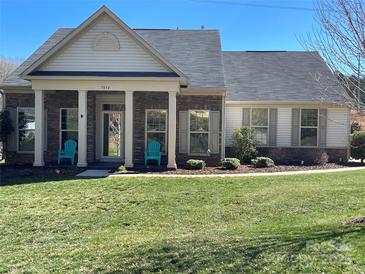 Charming home featuring a manicured lawn, stone accents, and inviting front porch with blue chairs at 7034 Pin Oaks Dr, Denver, NC 28037