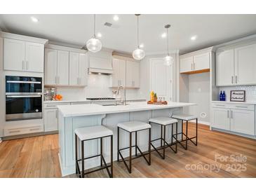 Bright kitchen features a large island with seating, stainless steel appliances, and modern light fixtures at 9930 Cask Way, Huntersville, NC 28078