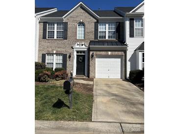 Charming brick townhome with a black front door wreath and a one car garage at 12031 Windy Rock Way # 1002, Charlotte, NC 28273