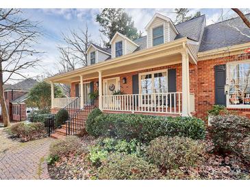 Charming brick home featuring a welcoming front porch, dormer windows, and beautifully landscaped front yard at 1531 Wheaton Nw Way, Concord, NC 28027