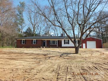 Charming brick home with a well-maintained lawn, complimented by a red barn and bare trees under a bright blue sky at 2739 Great Falls Hwy, Lancaster, SC 29720