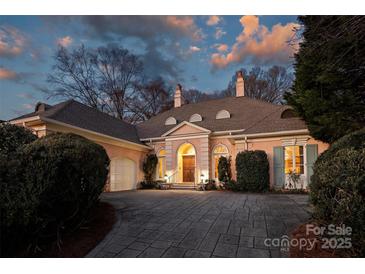 Elegant, light pink home featuring a circular driveway and well-manicured landscaping at dusk at 318 S Canterbury Rd, Charlotte, NC 28211