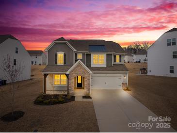 Beautiful two-story home boasting stone accents, attached garage, and lush front lawn at sunset at 367 Kennerly Center Dr, Mooresville, NC 28115