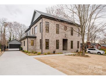 Elegant two-story brick home featuring a driveway leading to a detached garage and a well-maintained front yard at 412 Bertonley Ave, Charlotte, NC 28211