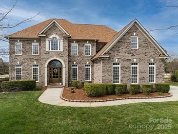 Charming brick home with a well-manicured lawn, beautiful landscaping, and an inviting front entrance at 5501 Two Iron Dr, Matthews, NC 28104