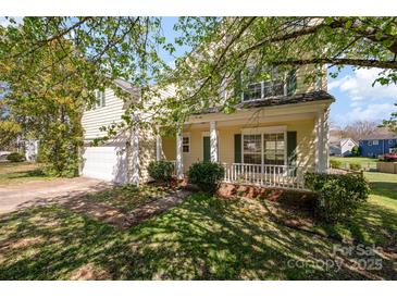 Charming two-story home boasts a welcoming front porch, attached garage, and beautiful landscaping at 6720 Neuhoff Ln, Charlotte, NC 28269