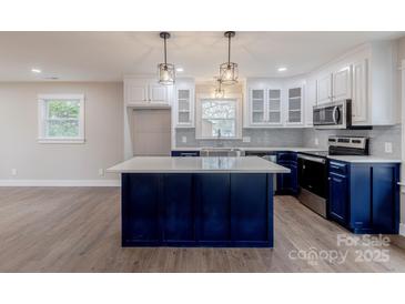 Bright, open kitchen featuring blue cabinets, quartz countertops, and stainless steel appliances at 1114 University Dr, Lancaster, SC 29720