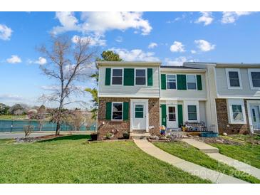 Charming townhome with a well-manicured lawn, brick accents, and delightful green shutters near a lake at 130 Water Oak Dr, Pineville, NC 28134