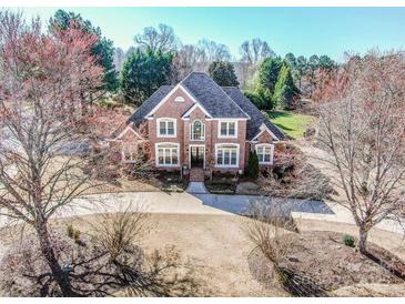 Beautiful two-story brick home featuring manicured landscaping, circular driveway, and mature trees at 17201 Royal Court Dr, Davidson, NC 28036