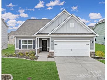 Charming single-Gathering home featuring a two-car garage and a well-manicured lawn under a bright, cloudy sky at 325 Ox Bow Cir, Mount Holly, NC 28120