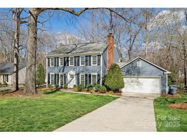 Charming two-story home with blue siding, black shutters, attached garage and a well manicured lawn at 4811 Dawnridge Dr, Charlotte, NC 28226