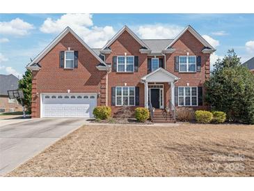 Charming red brick two-story home featuring a two-car garage, manicured lawn, and covered front entry at 5608 Old Town Ln, Gastonia, NC 28056