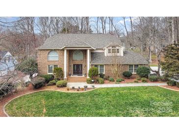 Charming two-story brick home with a lush green lawn, mature trees, and beautifully landscaped front yard at 8909 Abberley Ct, Huntersville, NC 28078