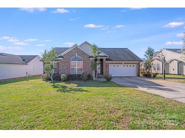 Charming brick home with a manicured lawn, two-car garage, and lush landscaping on a sunny day at 1232 Pressley Downs Se Dr, Concord, NC 28025