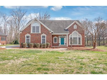 Charming brick home with a well-manicured lawn, blue front door, and bright windows at 7925 Tottenham Dr, Harrisburg, NC 28075