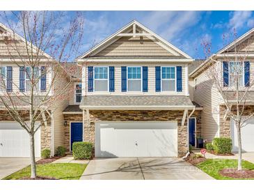 Charming two-story townhome featuring stone accents, a two-car garage, blue shutters, and a manicured lawn at 876 Summerlake Dr, Fort Mill, SC 29715