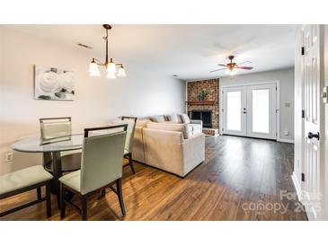 Inviting living room featuring hardwood floors, a brick fireplace, and a comfortable seating area at 10961 Carmel Crossing Rd, Charlotte, NC 28226