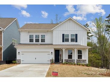 Charming two-story white home featuring stone accents, a two-car garage, and a welcoming front porch at 1439 Hubert Graham Way, Tega Cay, SC 29708