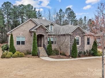 Charming home featuring a stone and brick exterior with a well-manicured lawn and professional landscaping at 16205 Bastille Dr, Charlotte, NC 28278