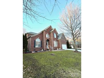 Charming two-story red brick home featuring well-manicured lawn, complemented by mature trees and lush landscaping at 205 Edenshire Ct, Indian Trail, NC 28079