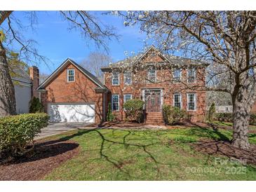 Charming two-story red brick home with a well-manicured lawn and blossoming trees at 7824 Hickory Stick Pl, Charlotte, NC 28277