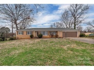 Charming brick ranch with a well-manicured lawn, mature trees, and attached garage at 107 Pinelake Dr, Kings Mountain, NC 28086