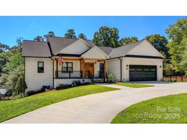 Inviting white brick home featuring a 2-car garage, covered porch, and well-maintained landscaping at 4808 1St Nw St, Hickory, NC 28601