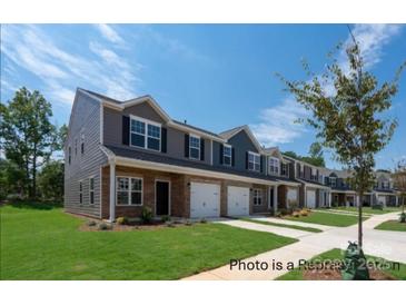 New townhome exterior with brick accents, attached garages, green lawn, and professional landscaping at #603 Mt. Mitchell Ave # 603, Gastonia, NC 28052