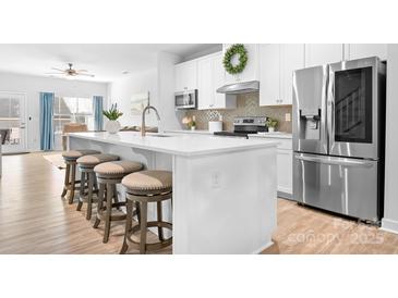 Bright kitchen boasts stainless steel appliances, a large island with seating, and white cabinetry at 781 Hazel Way, Denver, NC 28037