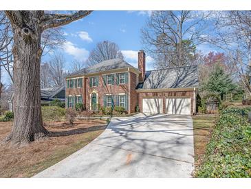 Brick home featuring a driveway leading to a 2-car garage, complemented by well-manicured landscaping and mature trees at 8807 Thornbury Ln, Huntersville, NC 28078