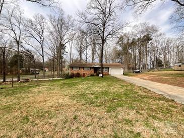 Charming brick home featuring an attached garage, spacious front yard, and long driveway surrounded by mature trees at 905 Kemper Cir, Rock Hill, SC 29732