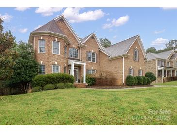 Traditional brick home with manicured lawn and detailed architectural features under a partly cloudy sky at 722 Fairway Point Dr, Fort Mill, SC 29708