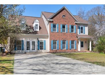 Charming two-story brick home featuring blue shutters, a well-manicured lawn, and a spacious driveway at 105 Easy St, Mooresville, NC 28117